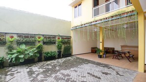 A courtyard with potted plants, a tiled floor, and a seating area with a table and chairs.