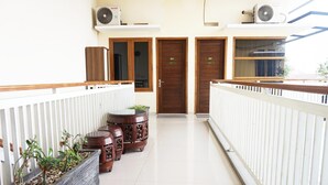 A clean, modern hallway with a white railing, wooden doors, and a potted plant arrangement.