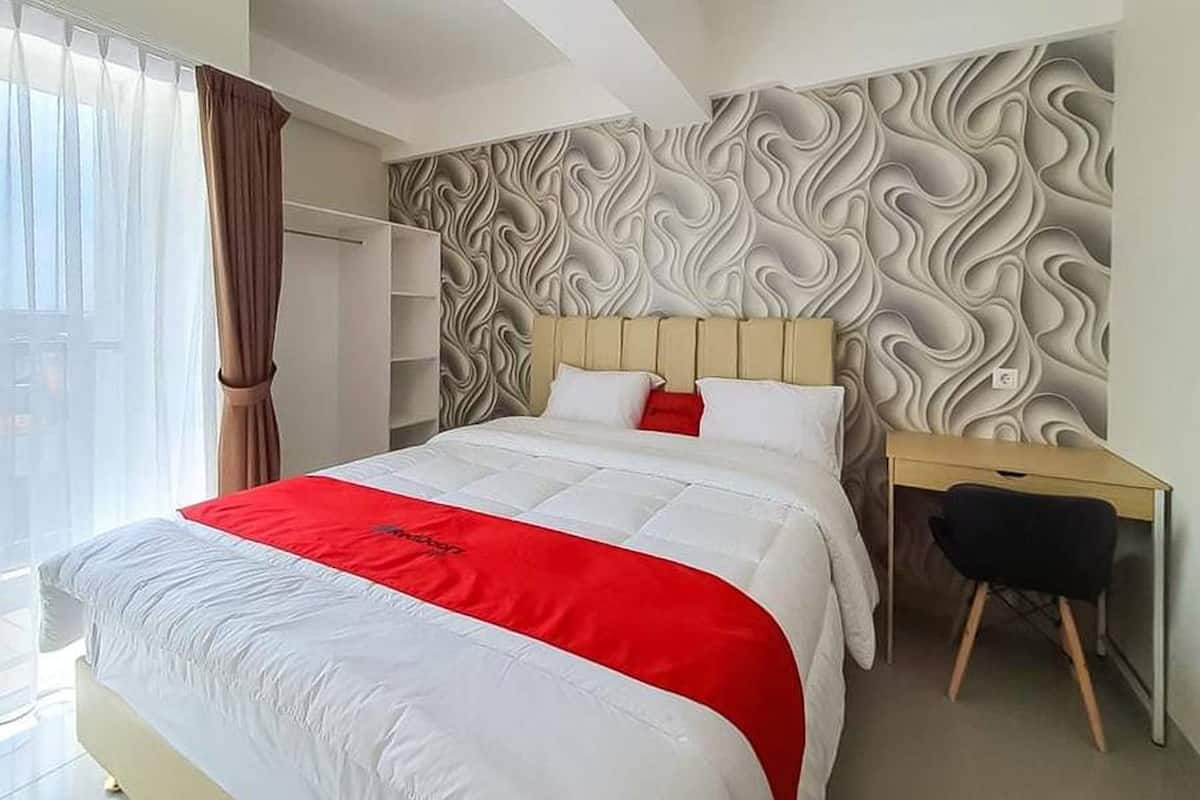 A modern hotel room with a large bed, a desk, and a wardrobe.