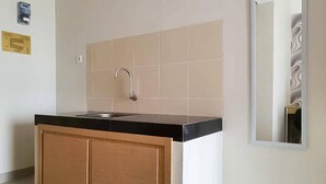 Cocina con encimera negra, armarios de madera y pileta de acero inoxidable.