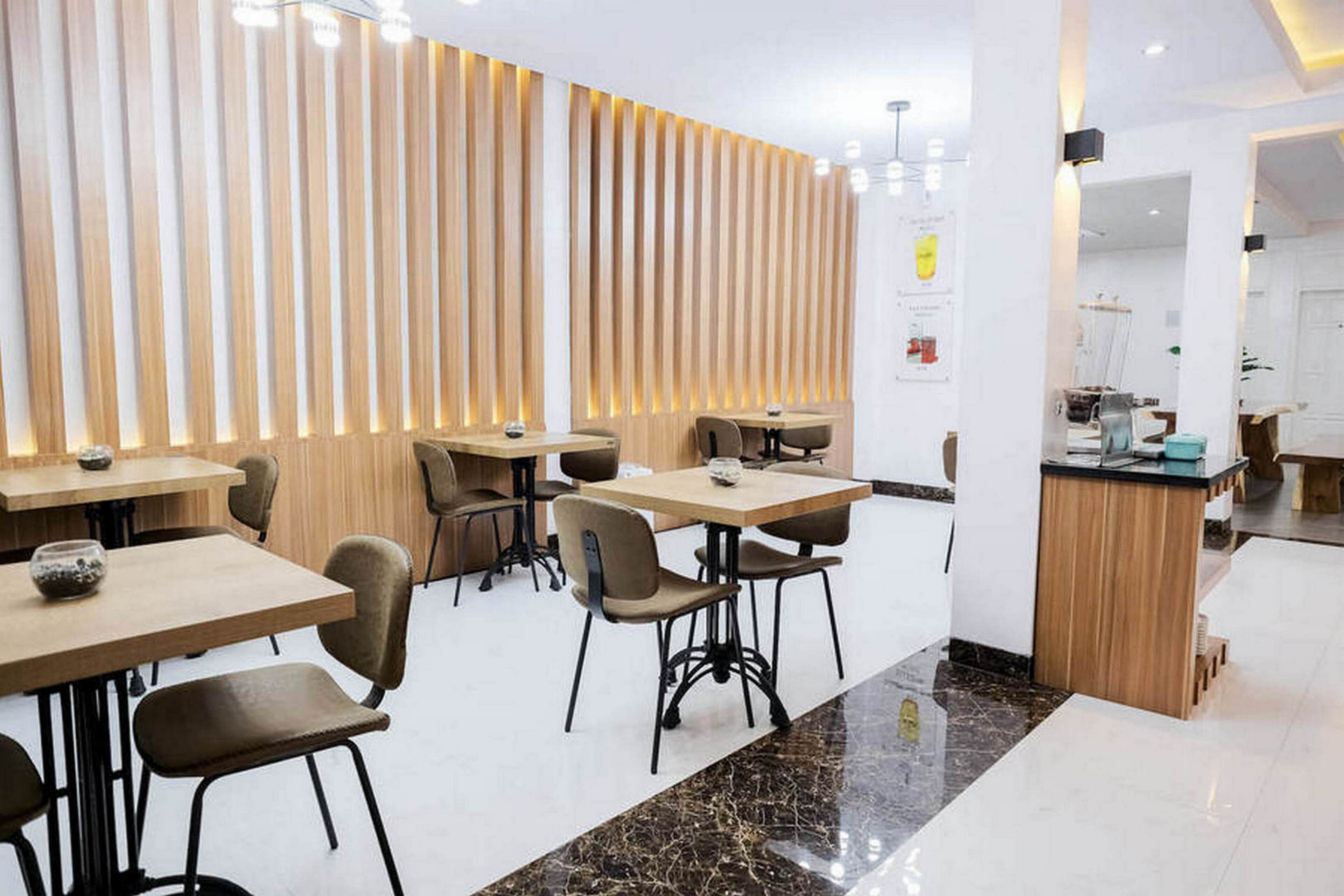 A modern restaurant interior with wooden panel walls, marble flooring, and a central island with a sink.