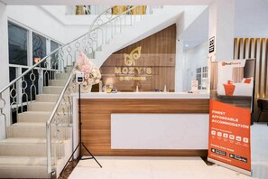 A reception desk with a wooden finish and a logo that reads "MOZY'S GUEST HOUSE".
