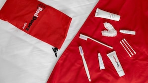 Articles d'higiene personal ordenats sobre un fons de teixit vermell i blanc.