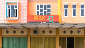 Un hotel con una fachada de color naranja brillante, una entrada con persianas verdes y un letrero que dice "Max to U HOTEL".