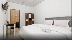 Une chambre d’hôtel équipée d’un lit, d’un bureau, d’une chaise, d’une armoire et d’un téléviseur fixé au mur.