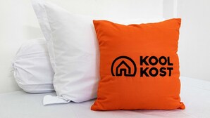 Deux oreillers, un blanc et un orange, portant un logo et une inscription.