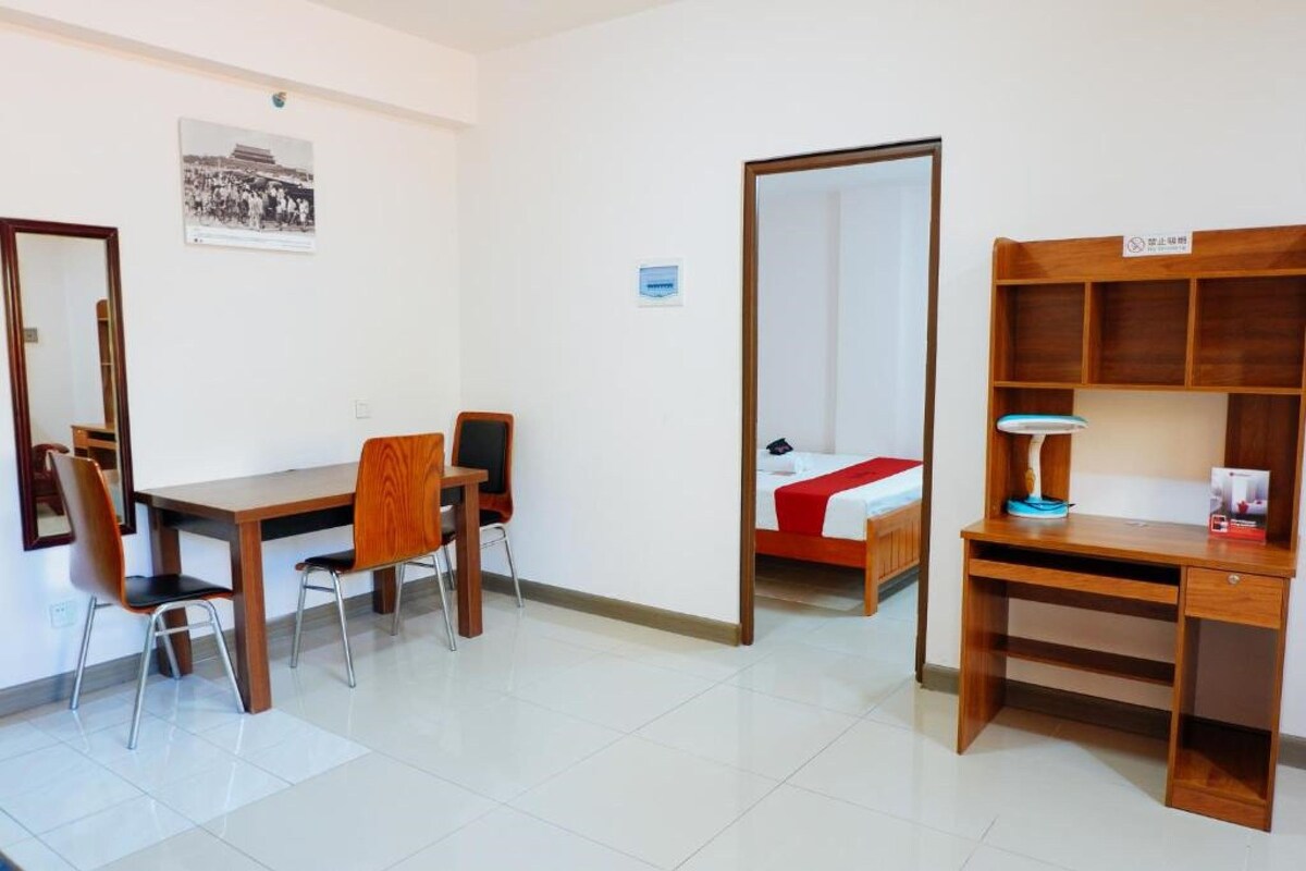Une chambre d’hôtel équipée d’un bureau, de chaises, d’un lit, d’une armoire et d’un miroir.