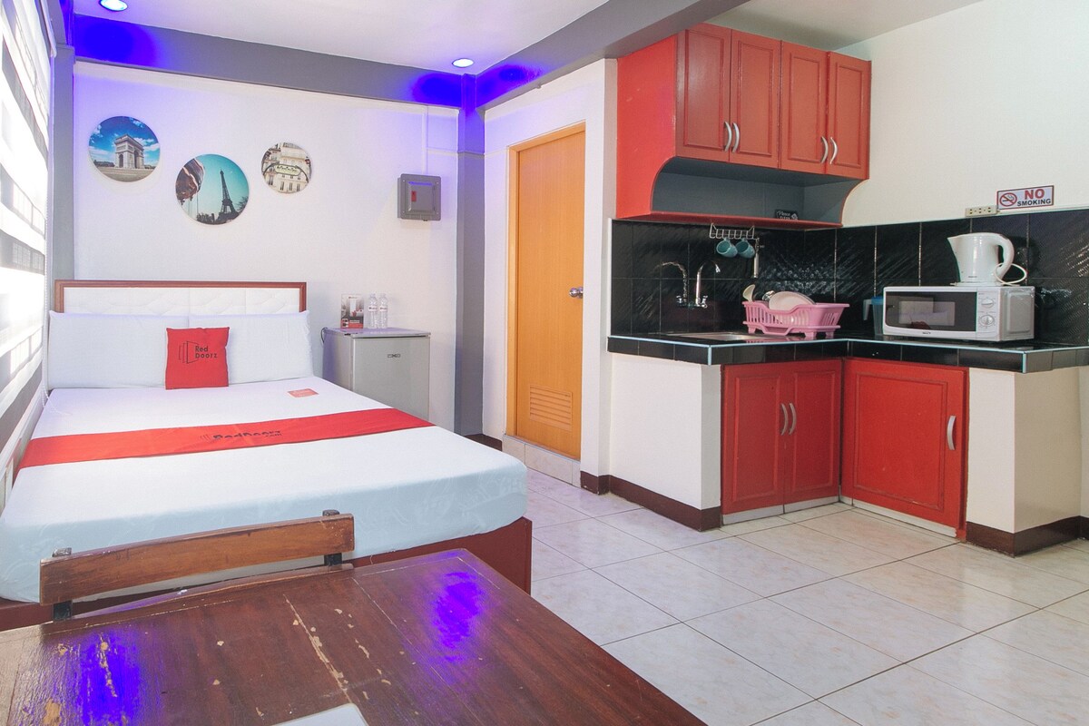 A hotel room with a bed, a small kitchenette, and a dining table.