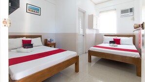 A hotel room with two beds, each with white linens and red accents, a wooden headboard, a small bedside table with a water bottle, and a framed picture on the wall. - RedDoorz Plus @ Santa Catalina Metro Vigan (Santa Catalina)