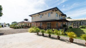 A two-story house with a balcony, a covered patio, and a well-maintained garden with potted plants. - RedDoorz Plus @ Santa Catalina Metro Vigan (Santa Catalina)