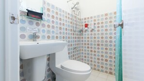 Ein Badezimmer mit weißem Waschbecken, Toilette und Dusche. Die Wände sind mit einem Punkte-Muster befliesst.