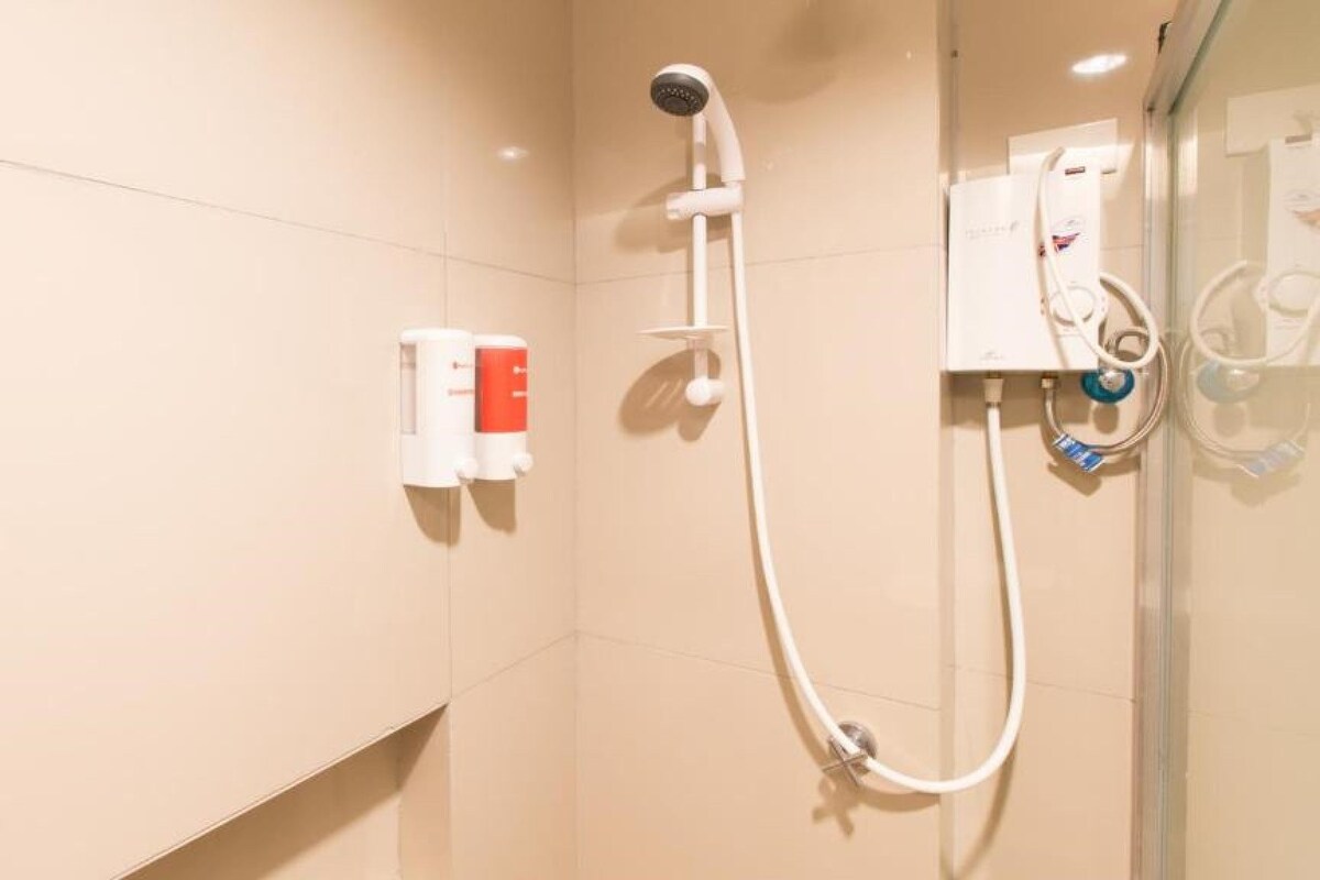 A shower with a handheld showerhead and a wall-mounted control panel.