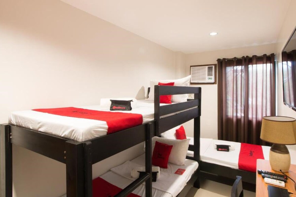A bunk bed room with a TV, a lamp, and a window with curtains.