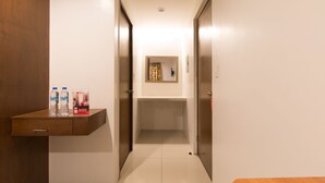 A hallway with a wooden desk, two water bottles, and a RedDoor sign. - RedDoorz Plus @ Diola Villamonte Bacolod (Bacolod)