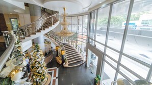 A multi-level atrium with a grand staircase, large windows, and a central chandelier. - RedDoorz Plus @ E Rodriguez Corner Banawe (Quezon City)