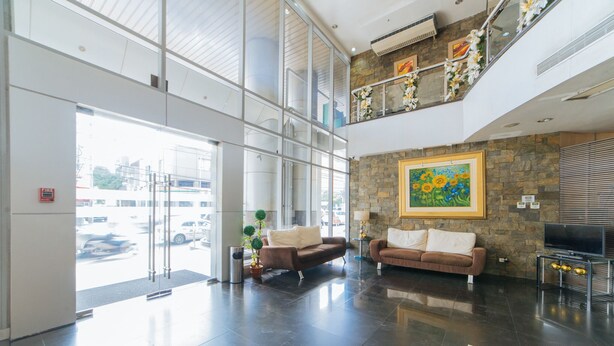 A spacious lobby with a high ceiling, large windows, and a stone accent wall. - RedDoorz Plus @ E Rodriguez Corner Banawe (Quezon City)