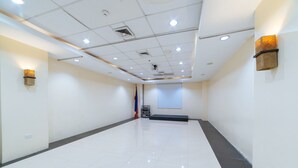 A spacious, well-lit conference room with a tiled floor, a projector screen, and a podium. - RedDoorz Plus @ E Rodriguez Corner Banawe (Quezon City)