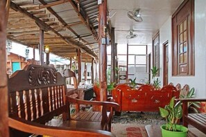A covered outdoor seating area with wooden furniture and potted plants. - RedDoorz Hostel @ Deomar Hometel & Farm Cafe Vigan Ilocos (San Vicente)