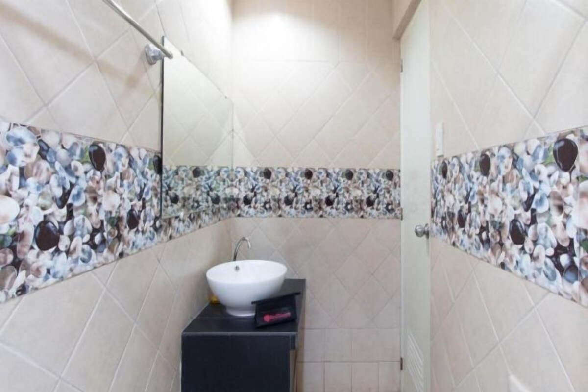 Un baño con un lavamanos blanco, un espejo y azulejos decorativos.