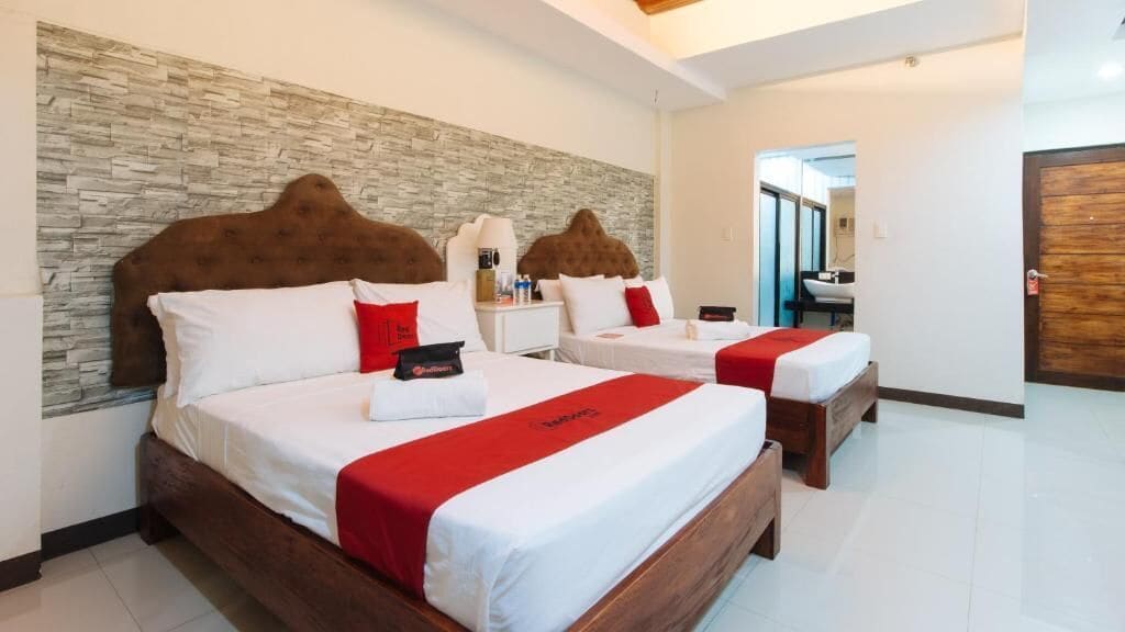 A hotel room with two beds, each with a wooden headboard and white bedding.