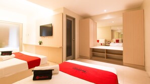 Une chambre d’hôtel avec deux lits, une télévision, un bureau et un miroir.