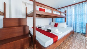 Une chambre avec un lit superposé, une tête de lit en bois, une literie blanche et un plaid rouge.