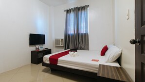 A hotel room with a bed, a TV, a nightstand, a red pillow, and a RedDoorz sign. - RedDoorz @ Golite Washington - Hostel (Legazpi)