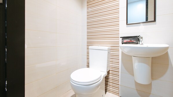 A bathroom with a toilet, a sink, and a striped wall. - RedDoorz @ Golite Old Albay - Hostel (Legazpi)