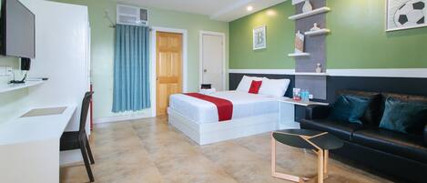 Habitación de hotel con cama, escritorio, silla, sofá y televisor.