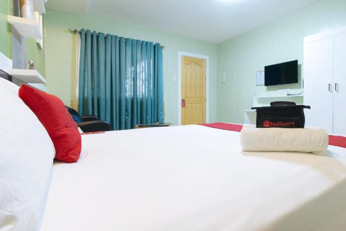 A hotel room with a large bed, a television on the wall, and a wardrobe.