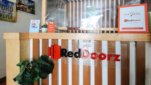 A RedDoorz reception desk with a wooden top and striped background. - RedDoorz near OWWA Pasay (Pasay)