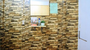 A stone wall with a RedDoorz sign, a water bottle, and a small plant on a shelf. - RedDoorz near OWWA Pasay (Pasay)