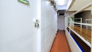 A narrow hallway with white walls, a tiled floor, and a wooden bench on the right. - RedDoorz near OWWA Pasay (Pasay)