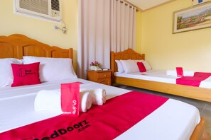 Habitación de hotel con dos camas, cada una con ropa blanca y detalles rojos, cabeceros de madera, mesitas de noche con lámparas y un cuadro en la pared.