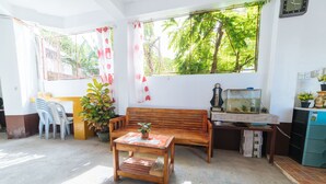 A room with a wooden bench, a small table with a plant, a fish tank, and a refrigerator.