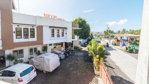 A hotel named Nikkyjm with a covered car and motorcycles parked outside.