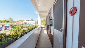 A corridor with a view of a pool and buildings, a fire extinguisher, and a red emergency pull station.