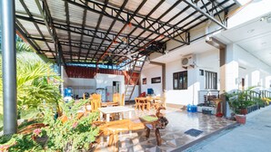 An outdoor patio area with wooden furniture, potted plants, and a tiled floor. - RedDoorz @ Bonifacio Extn Baler (Baler)