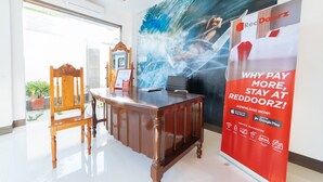 A reception desk with a wooden chair, a laptop, and a RedDoorz promotional poster. - RedDoorz @ Bonifacio Extn Baler (Baler)