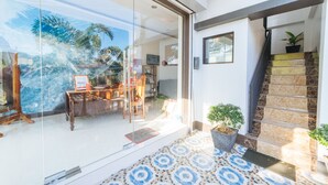 A modern interior with a glass door leading to a living area, a staircase with a potted plant, and a patterned floor. - RedDoorz @ Bonifacio Extn Baler (Baler)