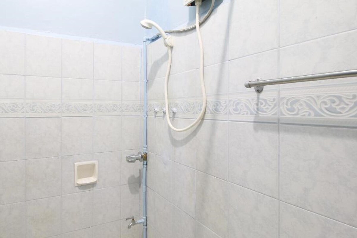 Doccia con soffione a mano e miscelatore montato a parete, porta asciugamani e piccolo portasapone.