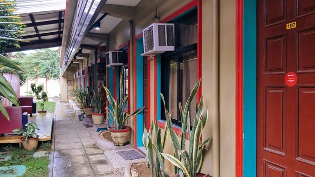 A row of rooms with red doors, air conditioning units, and potted plants. - RedDoorz @ Bankal Lapulapu (Lapu-Lapu)