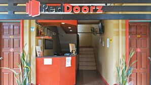 The entrance to Reed Doorz with a reception desk, two doors labeled 104 and 105, and a staircase leading inside. - RedDoorz @ Bankal Lapulapu (Lapu-Lapu)