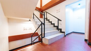 Un escalier avec des rampes noires et des marches blanches, menant à une pièce dotée d’une porte blanche et d’une enseigne sur le mur.