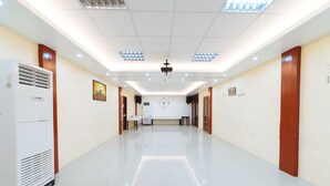 Un hall spacieux et bien éclairé, doté d’un design moderne, comprenant un projecteur fixé au plafond, un appareil de climatisation blanc et un sol propre et réfléchissant.