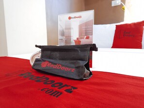 Un sac de la marque RedDoorz est posé sur un couvre-lit rouge, et le site web « RedDoorz.com » est visible.
