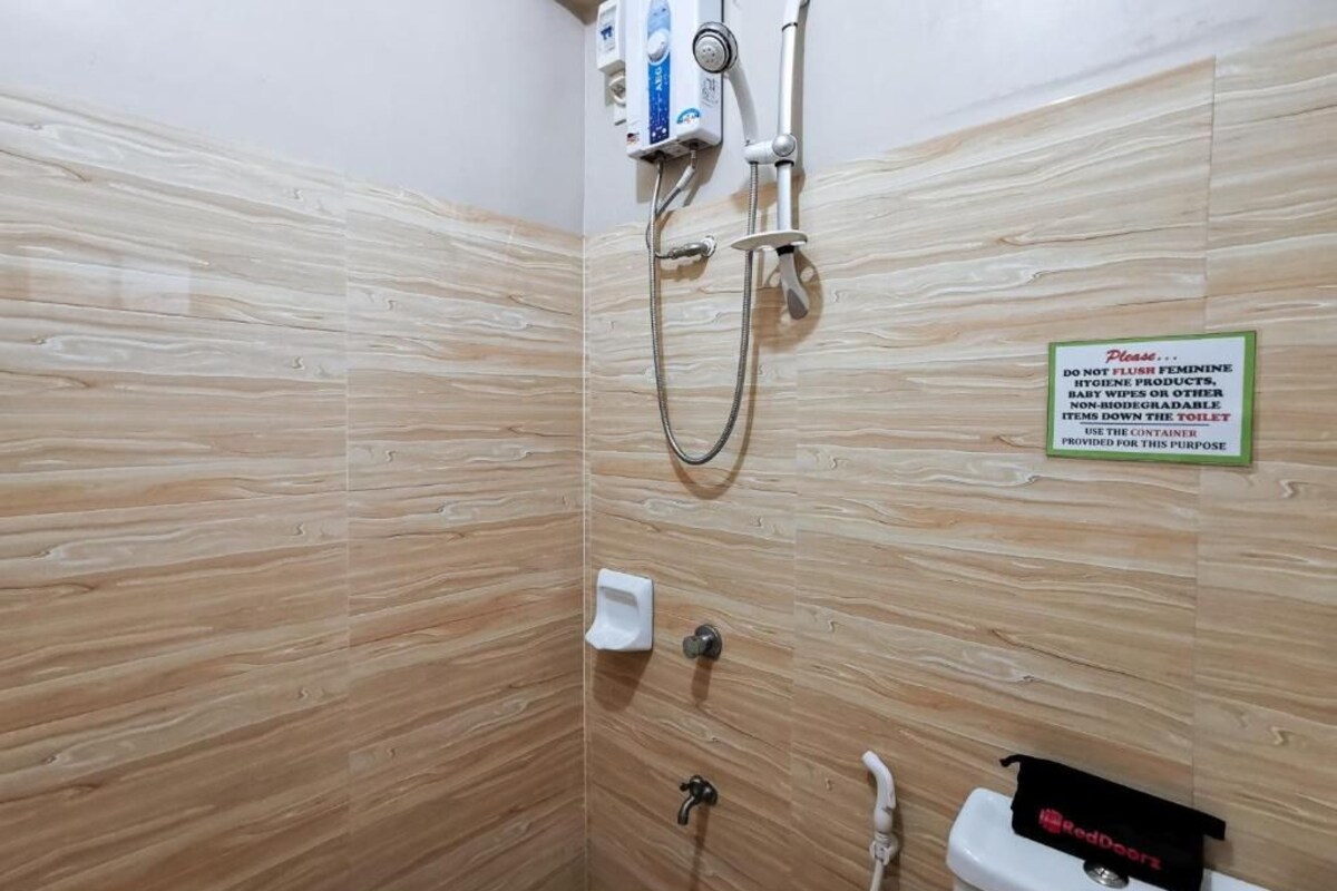 Une salle de bain équipée d’une douche, de toilettes et d’un lavabo. Un panneau indique qu’il est interdit de jeter les produits d’hygiène féminine dans les toilettes.