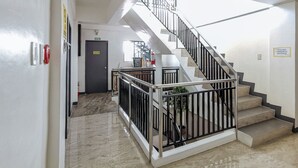 Vestíbulo de hotel con una escalera, un extintor y un letrero que solicita silencio.