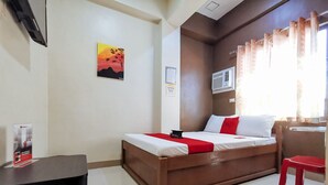 Una habitación de hotel con una cama, un escritorio, una silla y un cuadro en la pared.