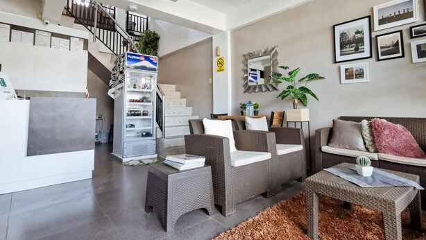 Una sala de estar moderna con una escalera, muebles de mimbre, un refrigerador y cuadros en la pared.